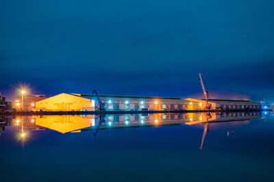 Illuminated built structure by sea against sky at night