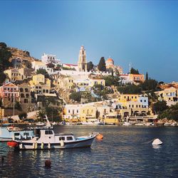 Sailboats in sea by townscape against clear blue sky