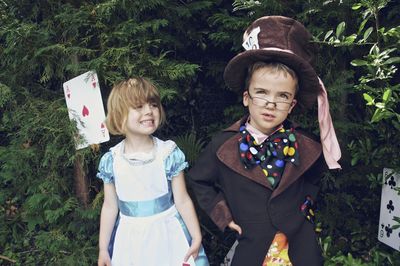 Boy and girl in costumes standing against trees