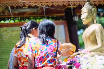 Women offering to bronze buddha statue during songkran festival on sunny day
