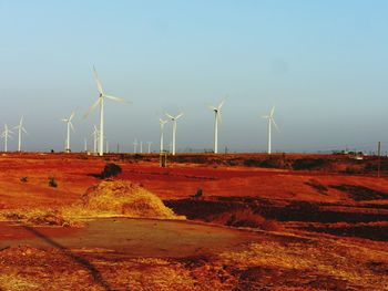 Windmills on field against sky