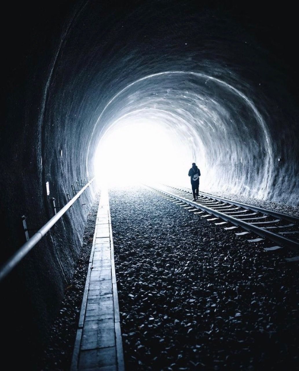 REAR VIEW OF SILHOUETTE MAN ON RAILROAD TRACK