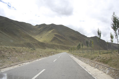 Road leading towards mountains against sky