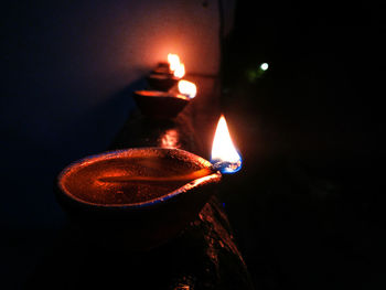 Close-up of lit candle light on retaining wall against black background