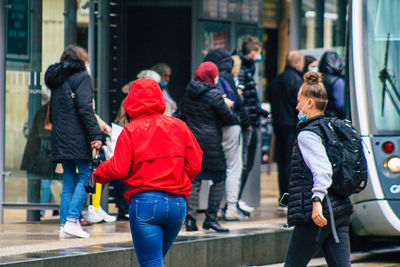 Rear view of people walking on street in city