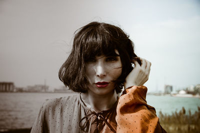 Portrait of young woman against sky