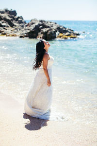 Full length of young woman standing on beach