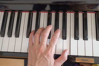 Cropped hand playing piano indoors