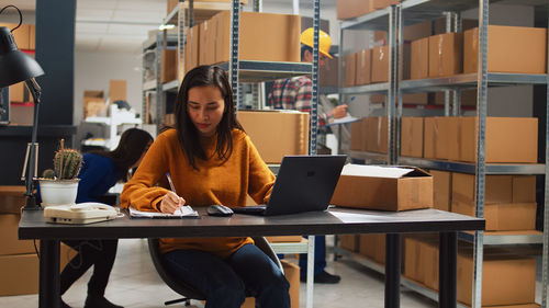 Young woman using laptop while sitting on table