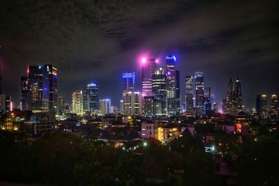 Illuminated buildings in city against sky at night