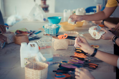 Cropped hands of women with art and craft equipment at table