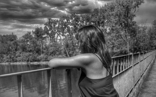 Rear view of woman standing by railing against trees