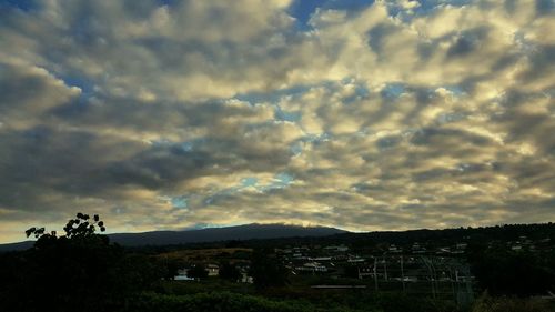 Houses on mountain against cloudy sky