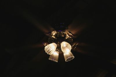 Low angle view of illuminated light bulb against black background