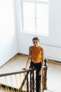 Portrait of young woman standing at steps railing