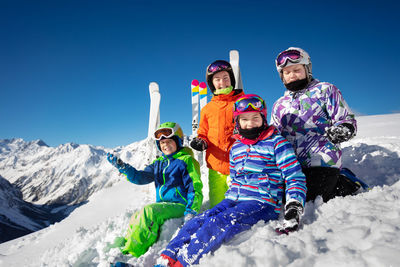 Rear view of man sitting on snowcapped mountain