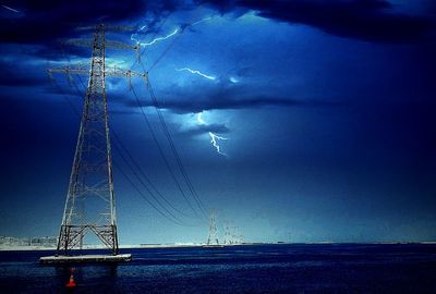 Electricity pylon against cloudy sky