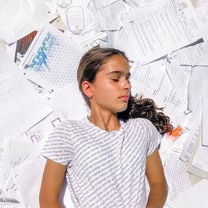 Girl sleeping on papers at home
