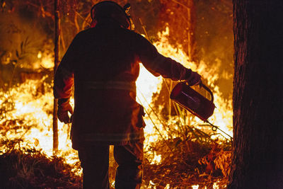 Rear view of man standing against orange sky