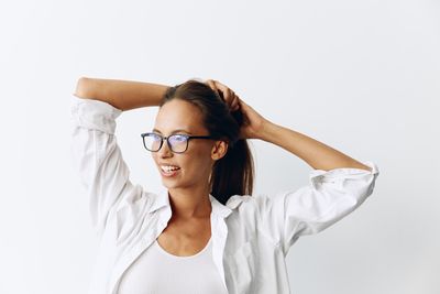 Portrait of young woman wearing sunglasses against white background