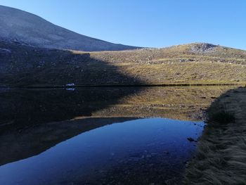 Scenic view of lake and mountains against clear blue sky