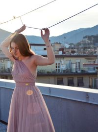 Woman standing by railing against sky