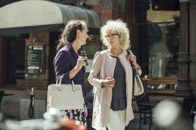 Senior women conversing while walking on city street