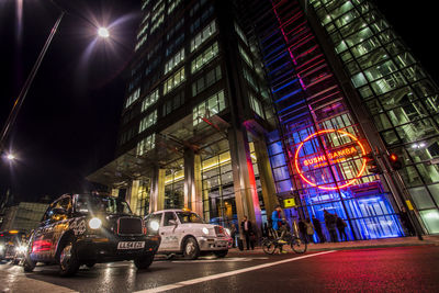 Illuminated street amidst buildings in city at night