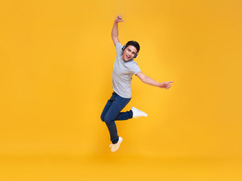 Portrait of man jumping against yellow background