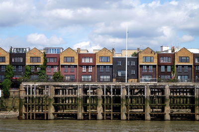 Residential buildings by river against sky