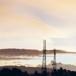 Silhouette poles on field against sky at dusk