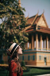 Side view of woman standing against building