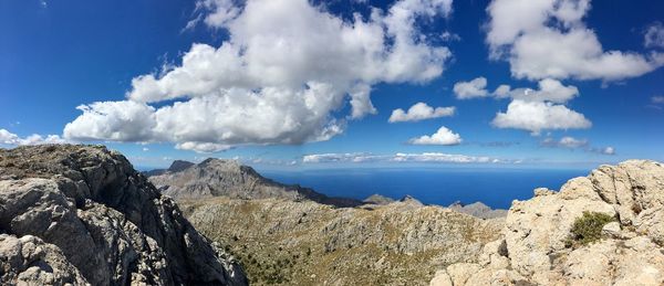 Panoramic view of rocky mountains against blue sky