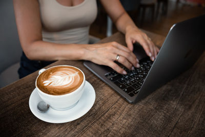 Midsection of woman using laptop at table