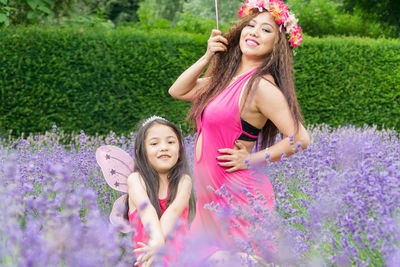 Portrait of smiling woman standing against purple flowering plants