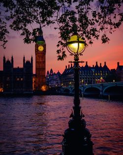 Close-up of lamp post by river against big ben at dusk in city