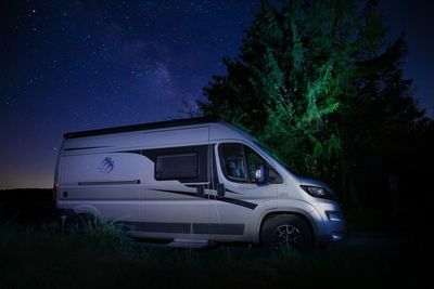 Car on field against sky at night