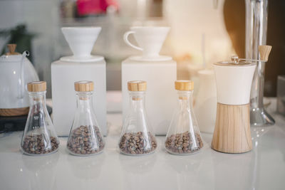 Close-up of coffee beans in glass bottles on table