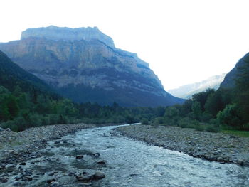 Scenic view of river by mountains against clear sky