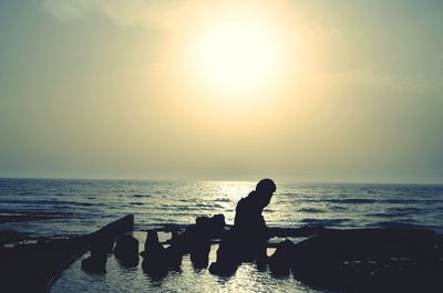 Silhouette man standing on beach against sky during sunset