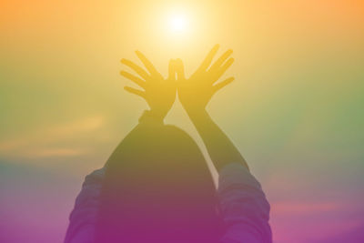 Midsection of woman standing against illuminated orange sky