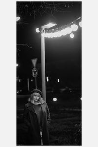 Portrait of woman standing against illuminated lights at night