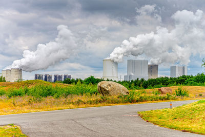 Smoke emitting from factory against sky