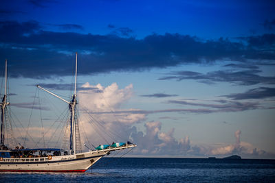 Ship sailing in sea against cloudy blue sky