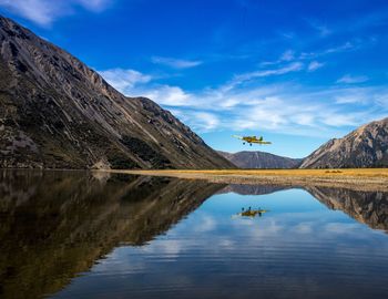 Scenic view of lake and mountains against blue sky