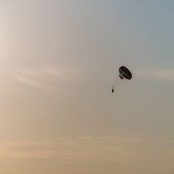 Low angle view of person paragliding against sky during sunset