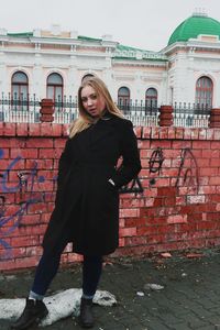 Portrait of woman standing against brick wall