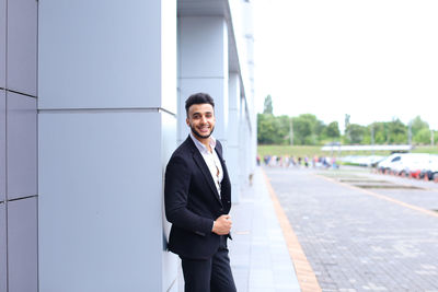 Portrait of businessman standing against building