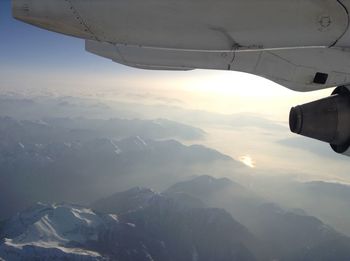 Cropped image of airplane flying over snowcapped mountains