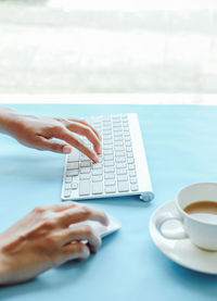 Cropped image of hand holding coffee cup on table